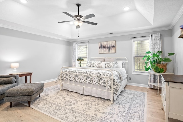 bedroom featuring multiple windows, a raised ceiling, ceiling fan, and crown molding