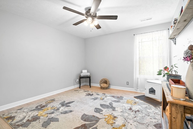 sitting room with hardwood / wood-style floors, a textured ceiling, and ceiling fan