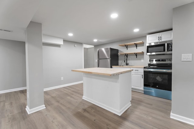 kitchen featuring a center island, sink, stainless steel appliances, light hardwood / wood-style floors, and white cabinets