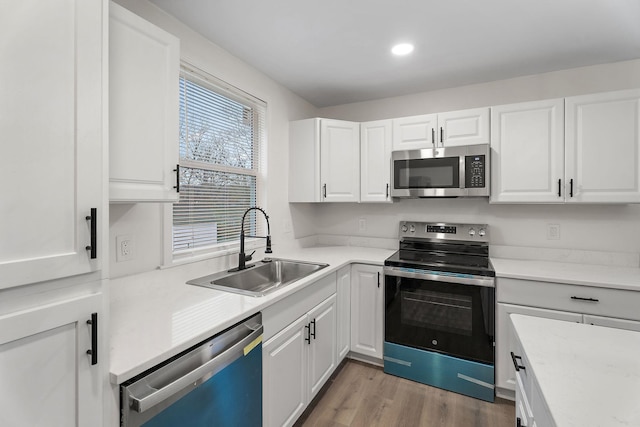 kitchen featuring light wood-type flooring, stainless steel appliances, white cabinetry, and sink