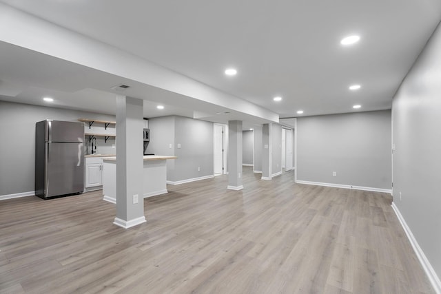 unfurnished living room with light hardwood / wood-style flooring and sink