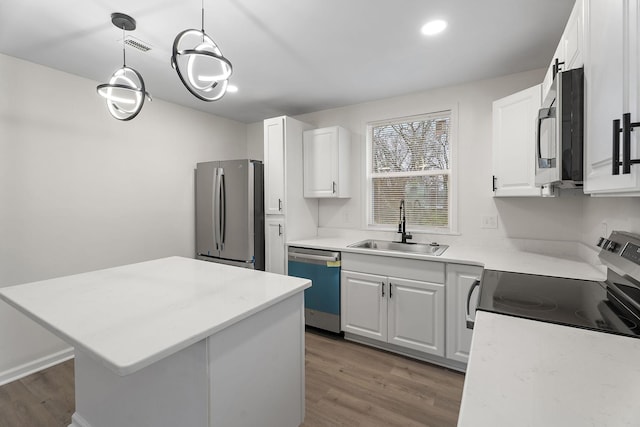 kitchen with stainless steel appliances, sink, white cabinets, a kitchen island, and hanging light fixtures