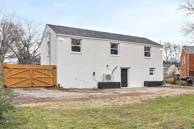 rear view of house featuring ac unit, cooling unit, and a lawn