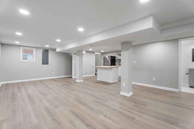 basement featuring electric panel, stainless steel fridge, and light hardwood / wood-style floors