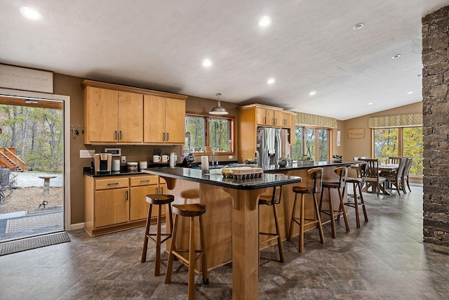 kitchen with a breakfast bar area, vaulted ceiling, stainless steel refrigerator with ice dispenser, a center island, and dark countertops