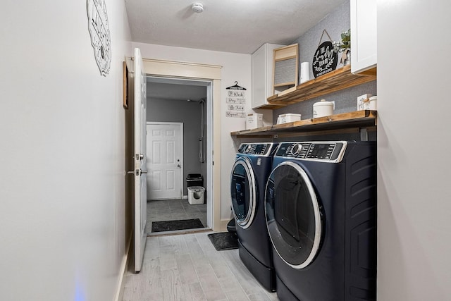 laundry area featuring baseboards, light wood-type flooring, cabinet space, and washer and dryer