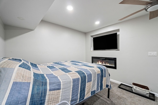 carpeted bedroom featuring recessed lighting, baseboards, and a glass covered fireplace