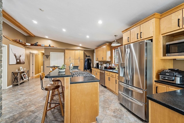 kitchen featuring stainless steel appliances, a kitchen breakfast bar, vaulted ceiling, an island with sink, and dark countertops