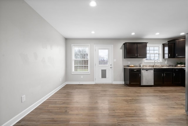 kitchen featuring dark brown cabinets, light hardwood / wood-style floors, stainless steel dishwasher, and a healthy amount of sunlight