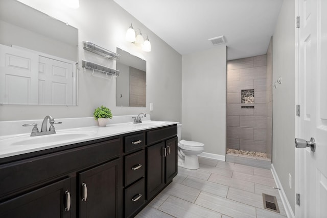 bathroom with a tile shower, vanity, and toilet