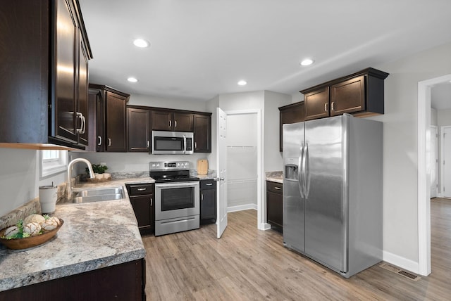 kitchen with light hardwood / wood-style floors, sink, dark brown cabinetry, and stainless steel appliances