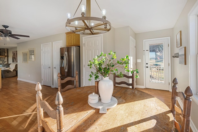 dining room with ceiling fan with notable chandelier and light hardwood / wood-style floors