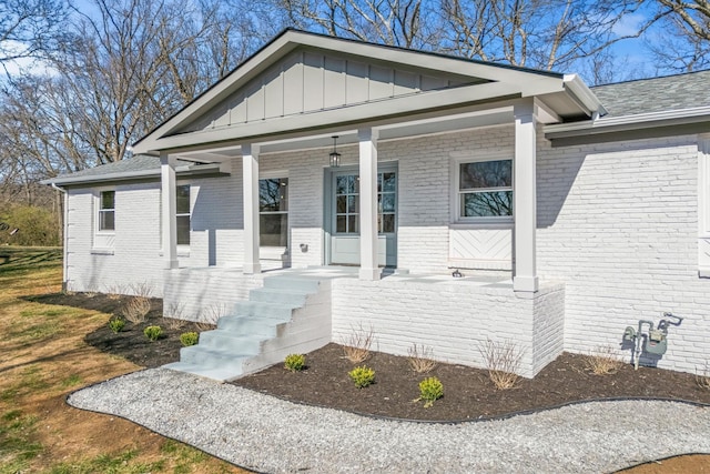 view of front of house featuring covered porch, board and batten siding, and brick siding