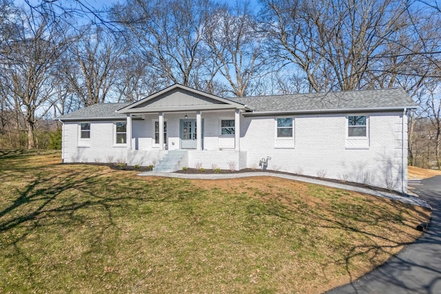 single story home with brick siding, a porch, a front lawn, and board and batten siding