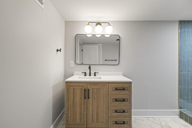 full bath featuring vanity, baseboards, and marble finish floor