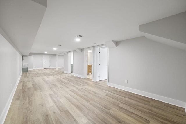 finished basement with visible vents, baseboards, and light wood-style floors