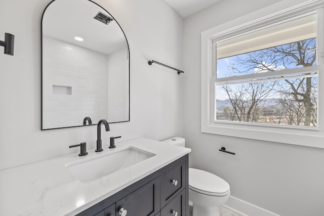 bathroom with toilet, vanity, and baseboards