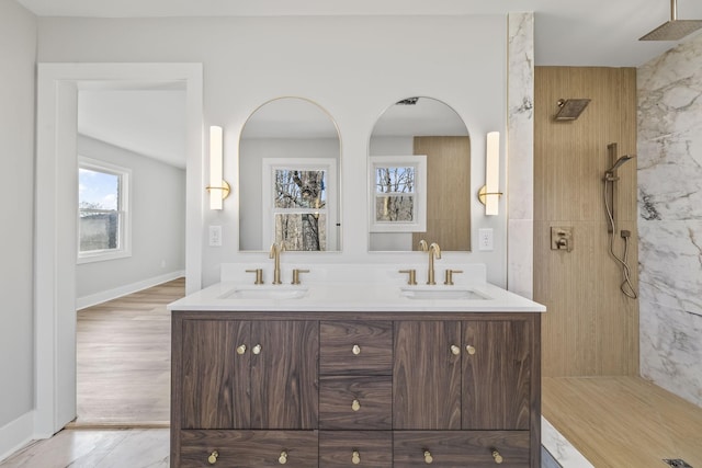 full bath featuring double vanity, a shower, baseboards, and a sink