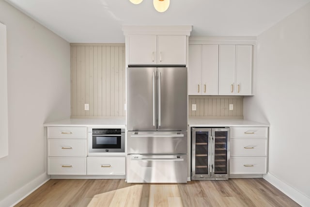 kitchen featuring wine cooler, white cabinets, appliances with stainless steel finishes, and light countertops