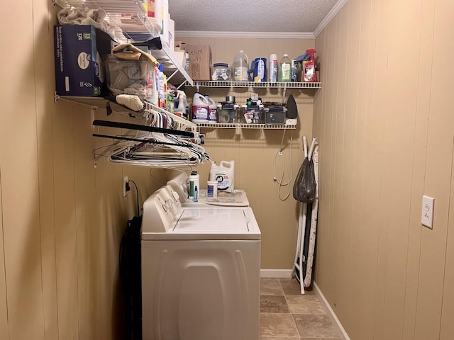 laundry area with a textured ceiling, washer and dryer, wood walls, and crown molding