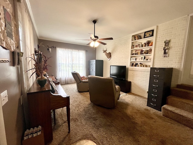 carpeted living room with ceiling fan, ornamental molding, and brick wall