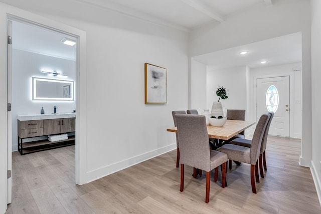 dining space with beam ceiling and light hardwood / wood-style floors