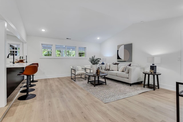 living room with light hardwood / wood-style flooring, lofted ceiling, and sink