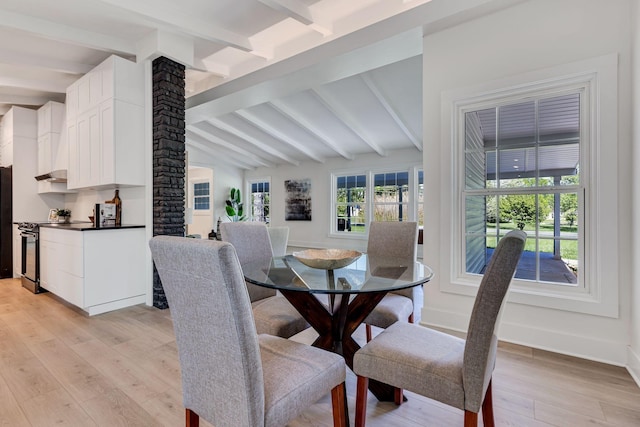 dining area with light wood-type flooring and lofted ceiling with beams