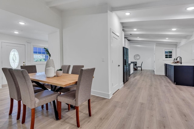 dining room featuring beamed ceiling, light hardwood / wood-style flooring, and sink