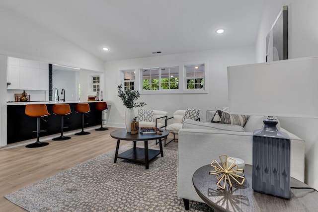 living room featuring lofted ceiling and light hardwood / wood-style flooring