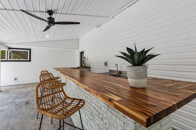 bar featuring wooden counters, vaulted ceiling, ceiling fan, and sink