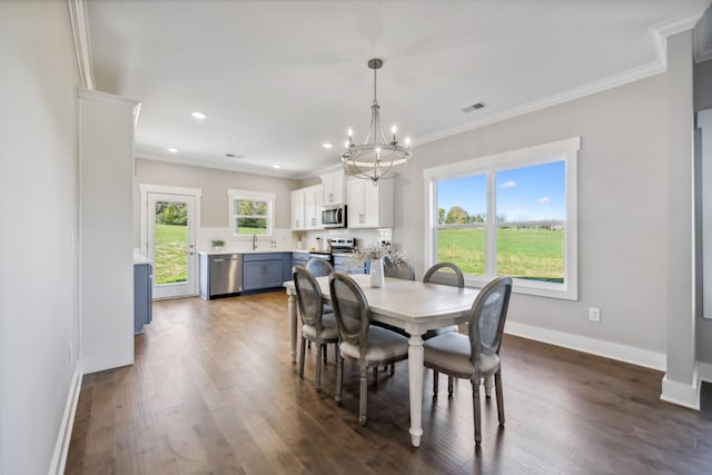 dining space featuring sink, dark hardwood / wood-style floors, ornamental molding, and a notable chandelier