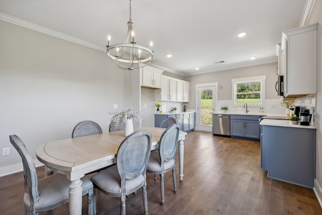 dining room featuring sink, ornamental molding, dark wood-type flooring, and an inviting chandelier