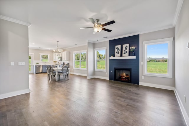 unfurnished living room featuring plenty of natural light, crown molding, a fireplace, and ceiling fan with notable chandelier