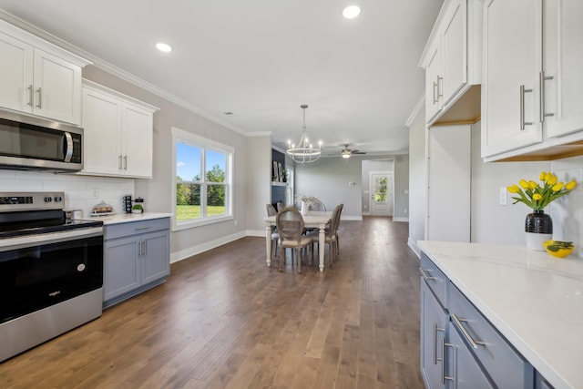 kitchen featuring white cabinets, ceiling fan with notable chandelier, crown molding, hanging light fixtures, and stainless steel appliances