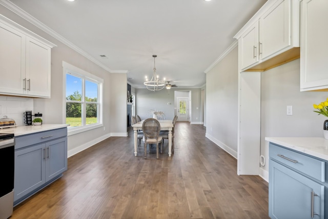 kitchen with white cabinetry, hanging light fixtures, light stone counters, dark hardwood / wood-style flooring, and ornamental molding