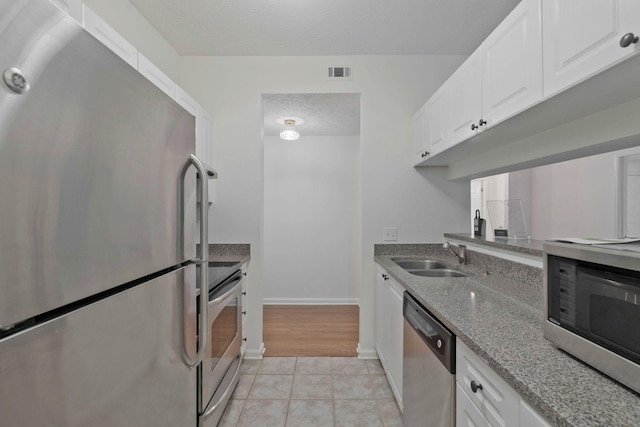 kitchen featuring sink, stainless steel appliances, a textured ceiling, stone countertops, and white cabinets