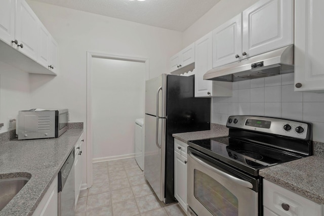 kitchen with appliances with stainless steel finishes, backsplash, white cabinets, washer / clothes dryer, and light tile patterned flooring