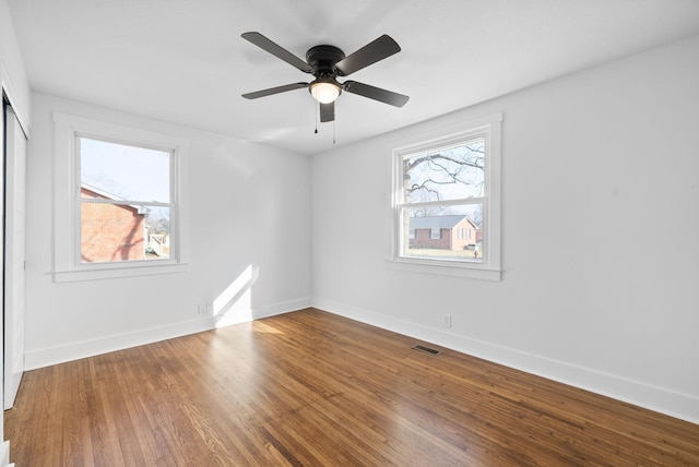 unfurnished room with wood-type flooring, a wealth of natural light, and ceiling fan