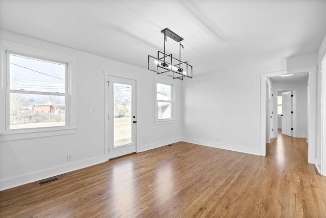 unfurnished dining area featuring hardwood / wood-style floors and a notable chandelier