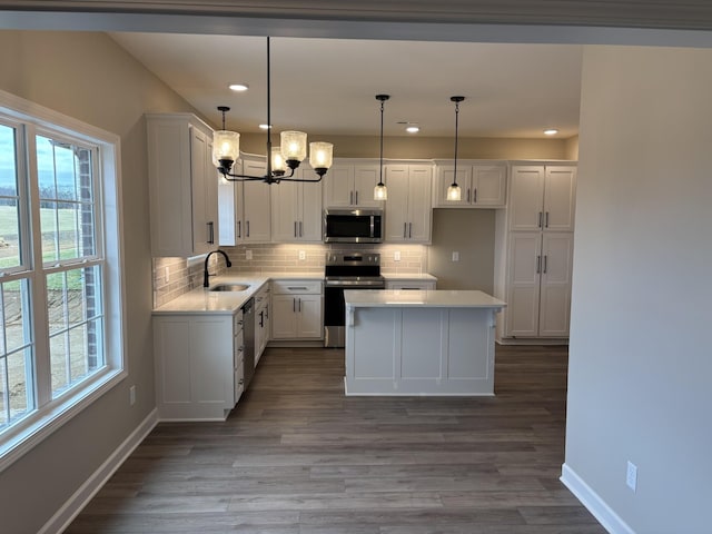 kitchen with appliances with stainless steel finishes, pendant lighting, tasteful backsplash, white cabinetry, and sink