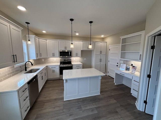 kitchen featuring sink, appliances with stainless steel finishes, white cabinetry, hanging light fixtures, and a center island