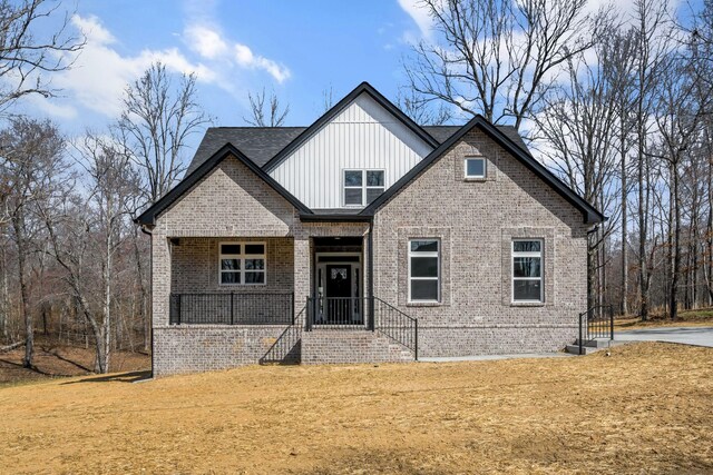 view of front facade featuring board and batten siding, a front lawn, a porch, and brick siding