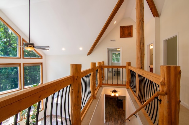 hall with beamed ceiling, a healthy amount of sunlight, and high vaulted ceiling