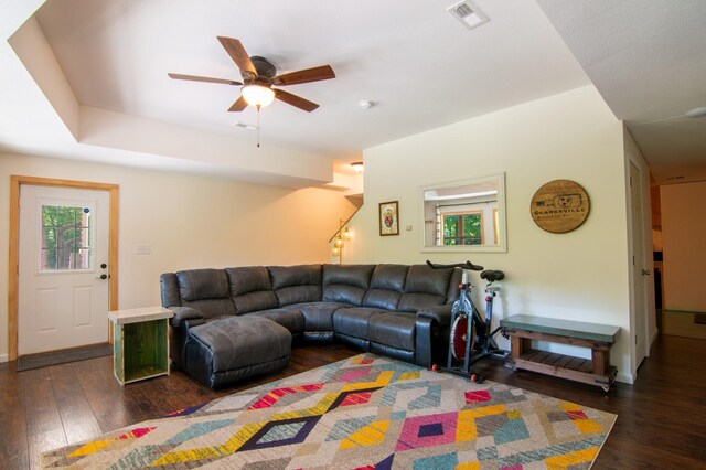 living room featuring dark wood-type flooring, ceiling fan, and plenty of natural light