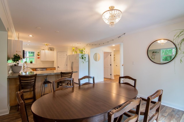 dining space featuring an inviting chandelier, sink, hardwood / wood-style flooring, and ornamental molding