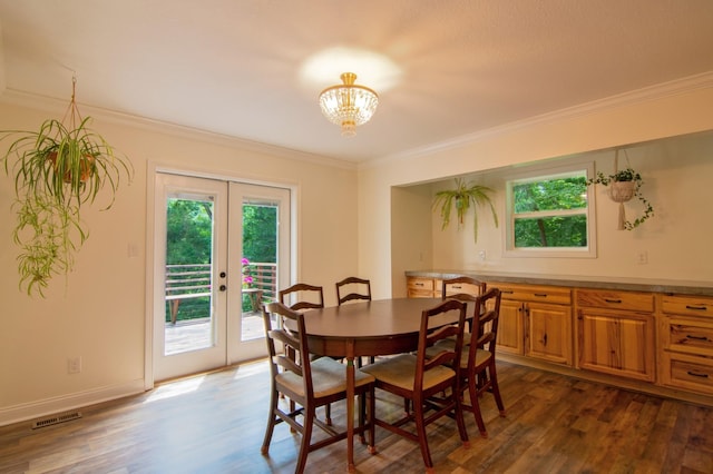 dining room with crown molding, dark hardwood / wood-style floors, an inviting chandelier, and french doors