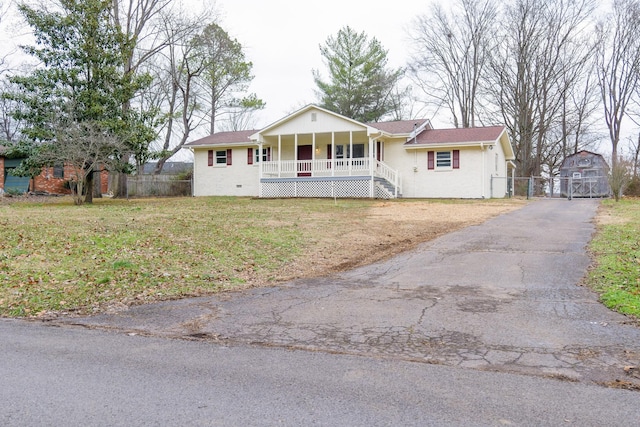 ranch-style home with covered porch, a front lawn, and an outdoor structure