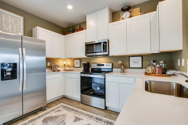 kitchen featuring white cabinetry, sink, stainless steel appliances, and light wood-type flooring