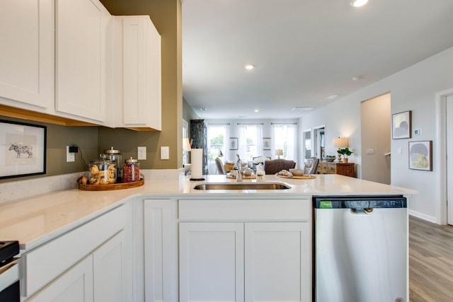 kitchen featuring white cabinetry, dishwasher, sink, light hardwood / wood-style flooring, and kitchen peninsula